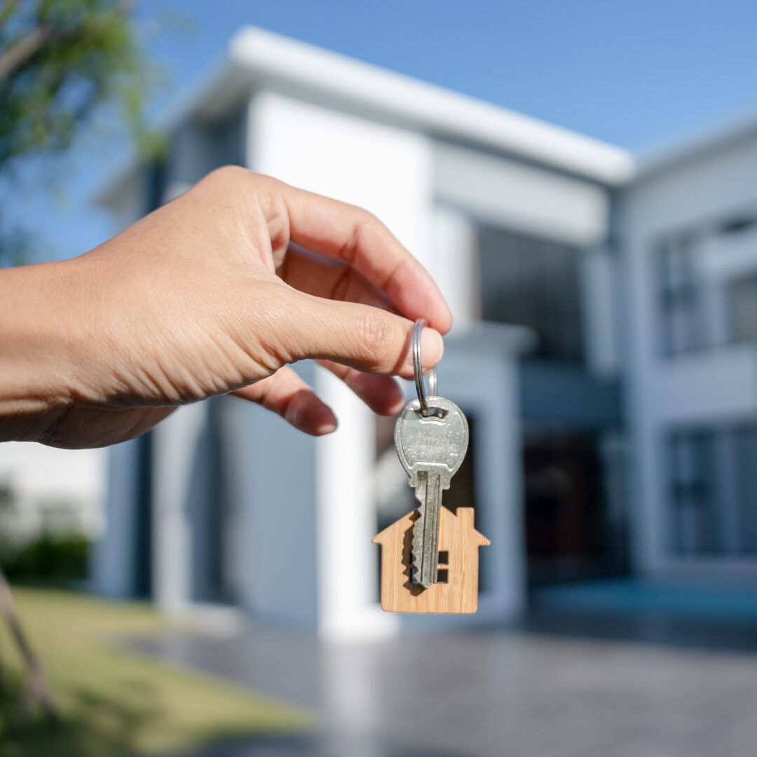 first-time homebuyer holding keys up in front of their home.