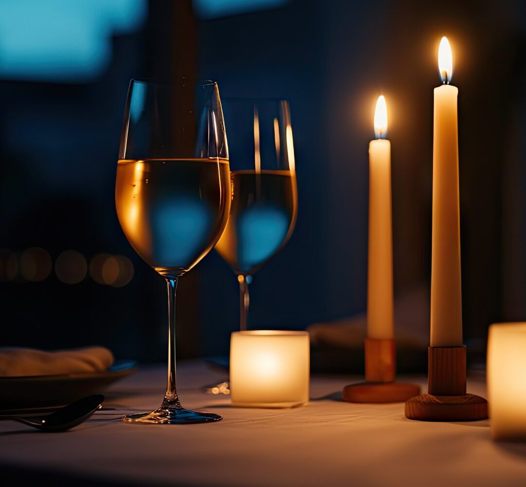 Close up of two wine glasses on a candlelit table representing dinner on Valentine's Day in San Antonio.